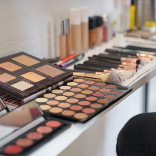 Make-up-Station mit Lidschattenpaletten, Pinseln und weiteren Kosmetikprodukten für eine Beratungssession